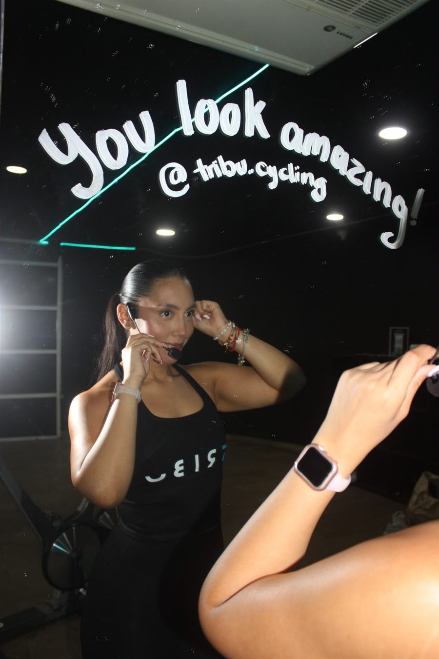 Viola, coach de TRIBU, frente al espejo del estudio con el mensaje You look amazing @tribu.cycling